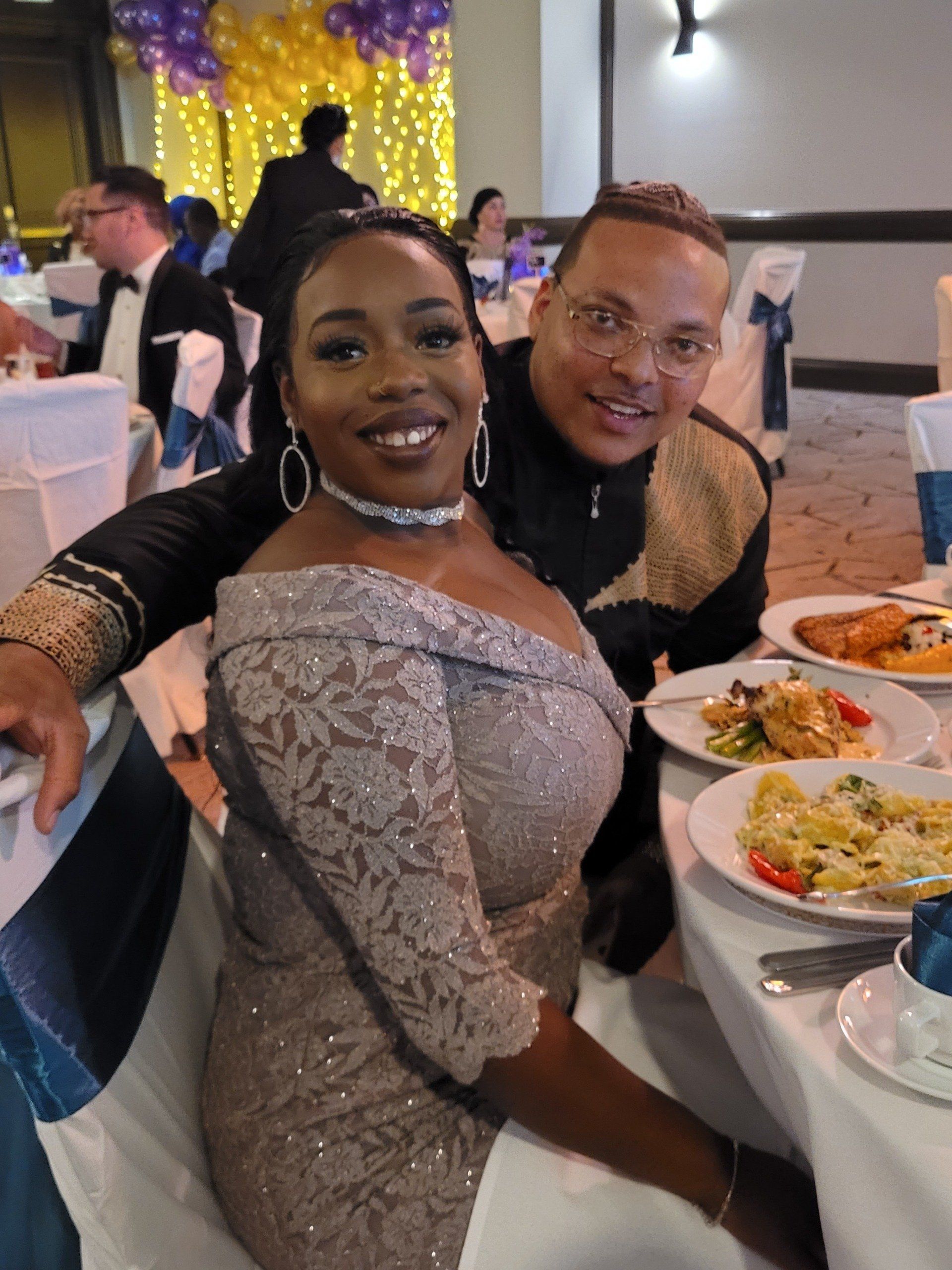 A man and a woman are sitting at a table with plates of food.