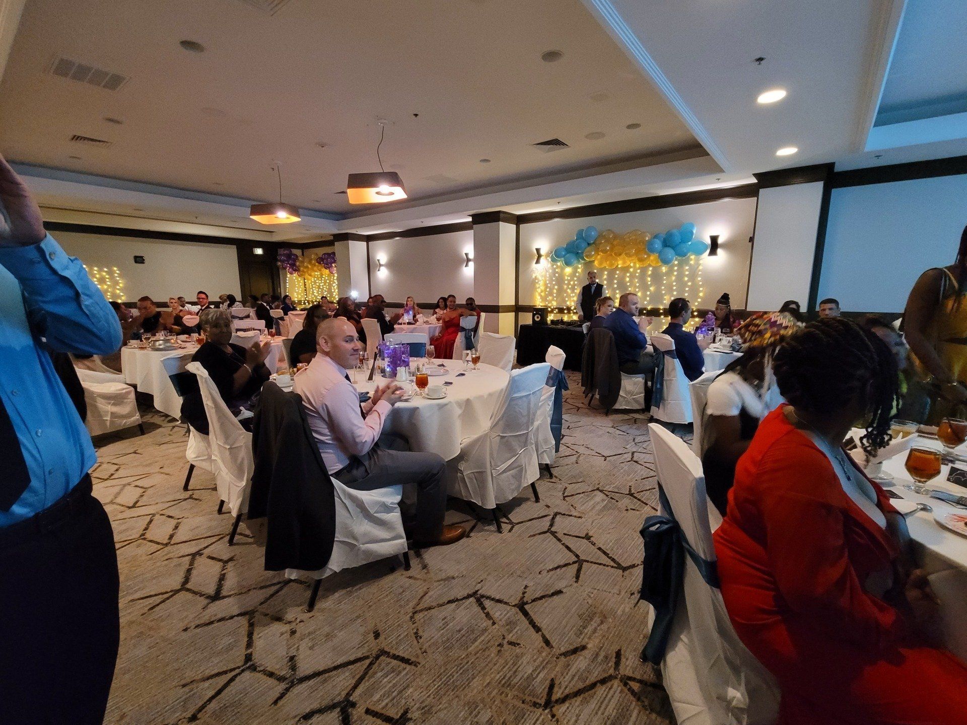 A group of people are sitting at tables in a large room.
