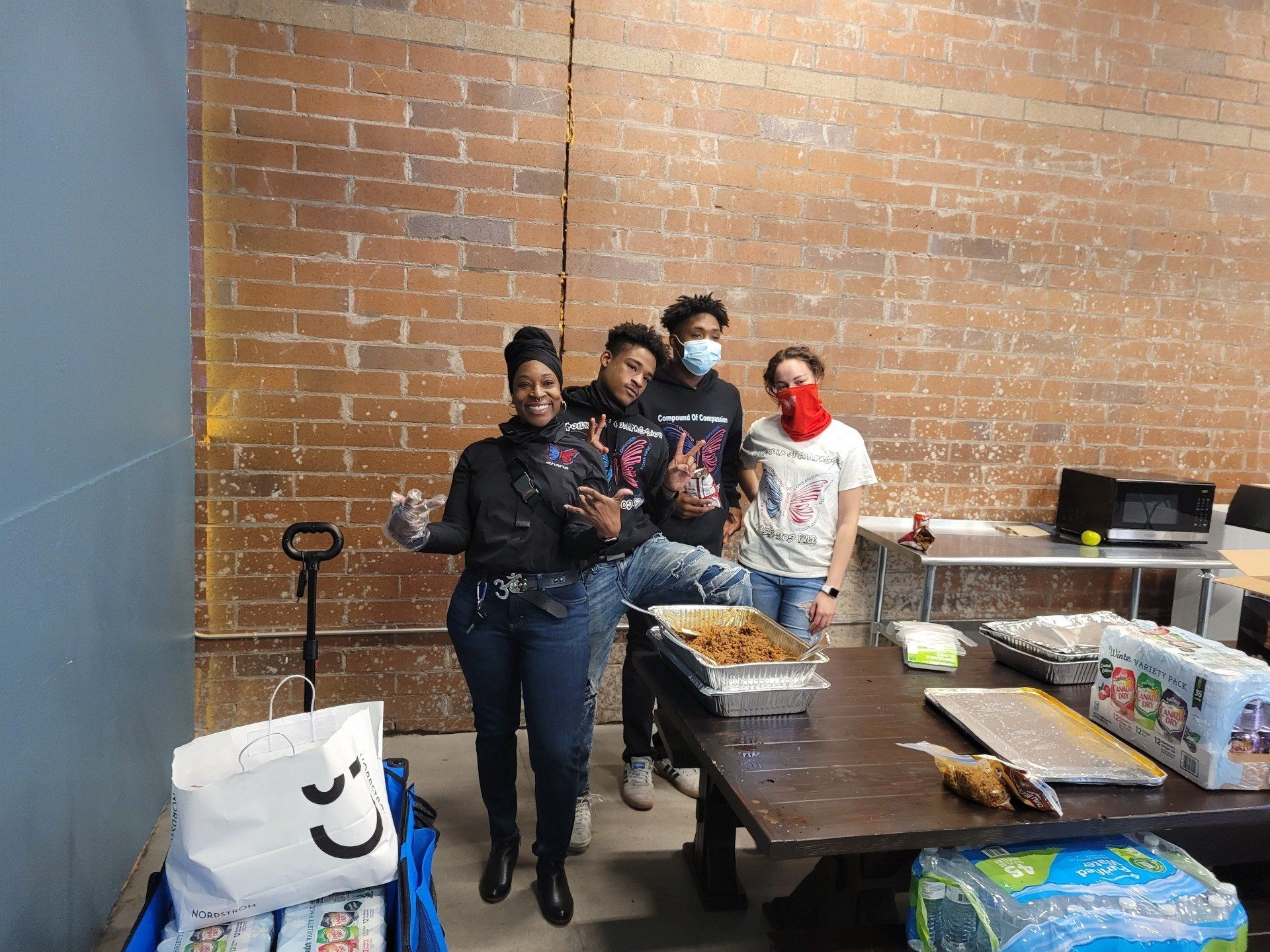 A group of people wearing face masks are standing around a table.