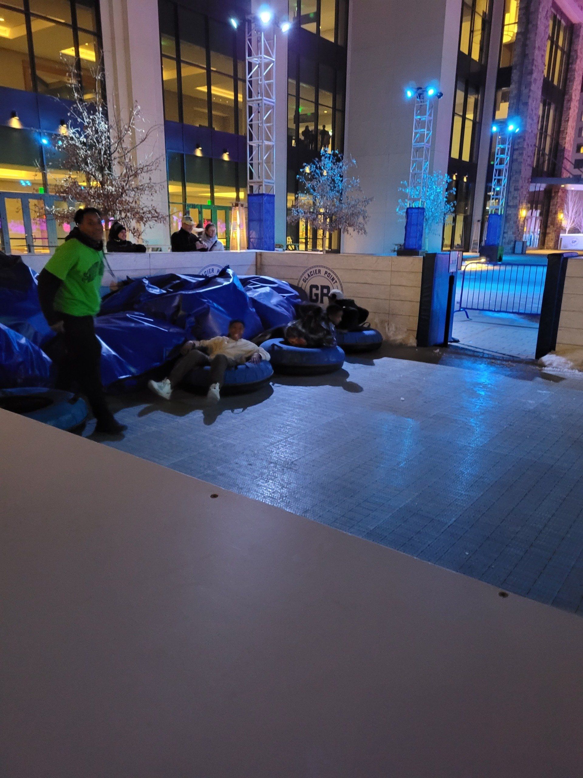 A man in a green shirt is standing next to a pile of snow tubes.