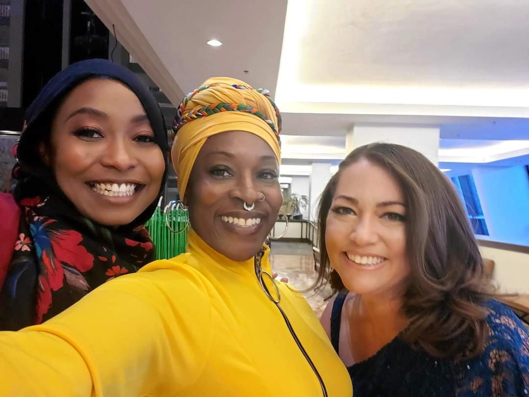 Three women are posing for a picture together and smiling