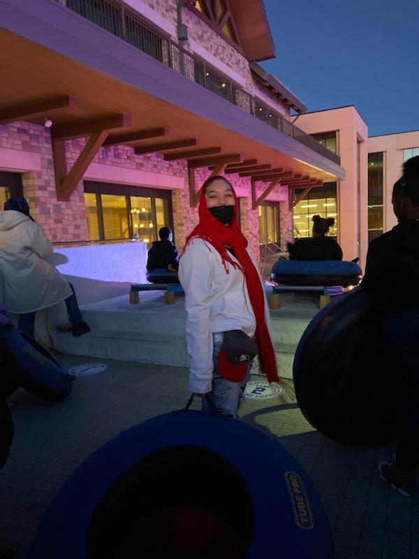 A woman wearing a red scarf is standing in front of a building