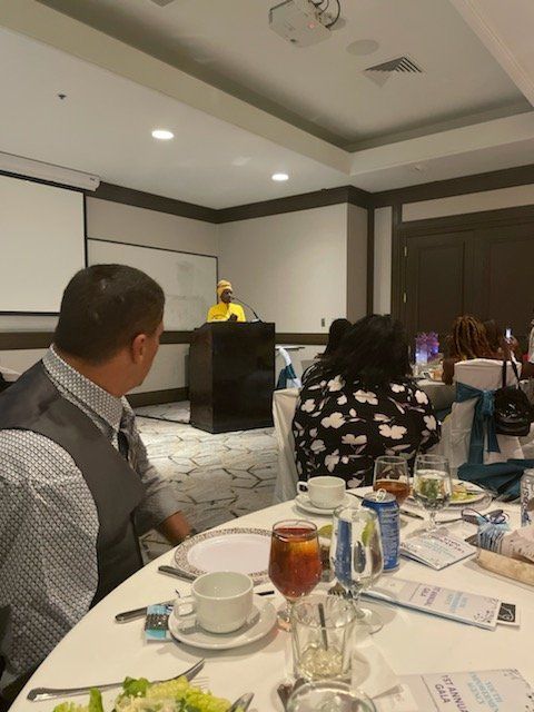 A man sits at a table in front of a projector screen