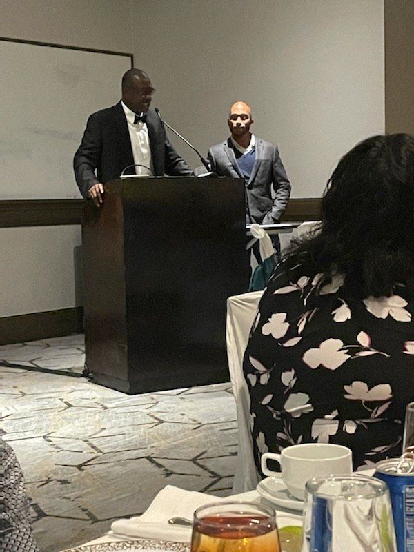 A man is standing at a podium giving a speech to a group of people.