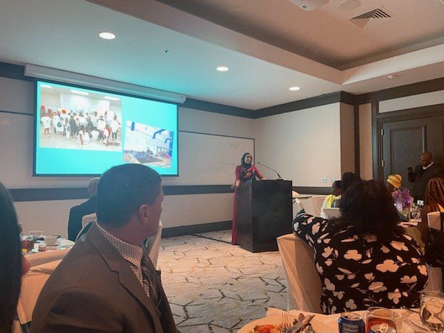 A woman is giving a presentation in front of a large screen in a conference room.