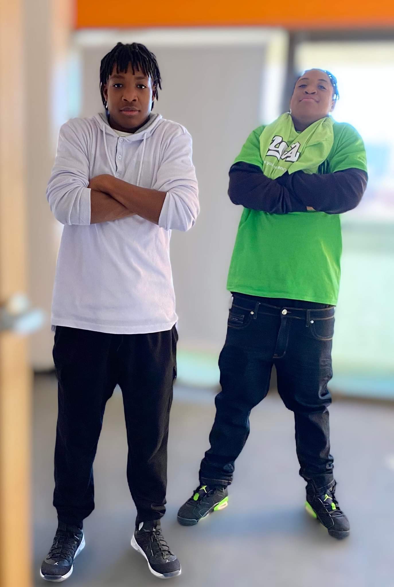 Two men are standing next to each other with their arms crossed.