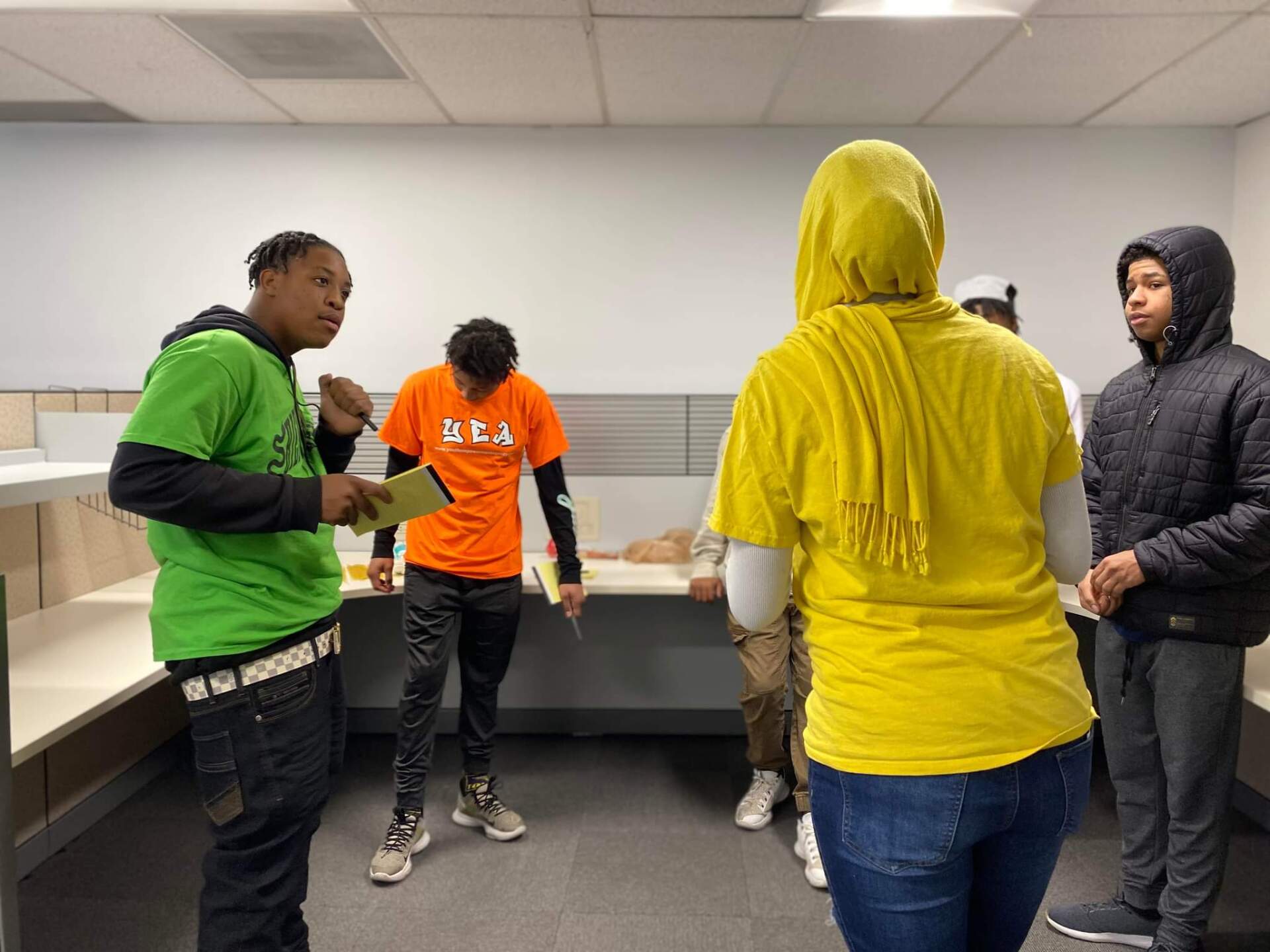 A group of people are standing in a room talking to each other.