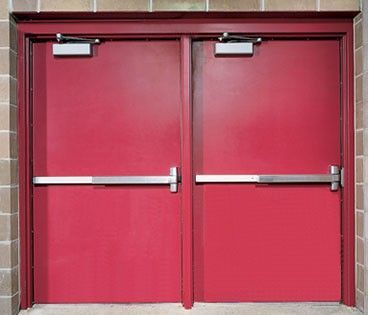Double red exit doors with silver push bars and closers