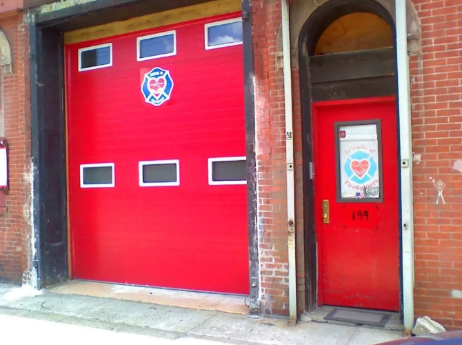 Red garage bay and red side door in a brick fire station exterior