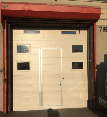 Cream garage door with small windows under a red awning at a building entrance