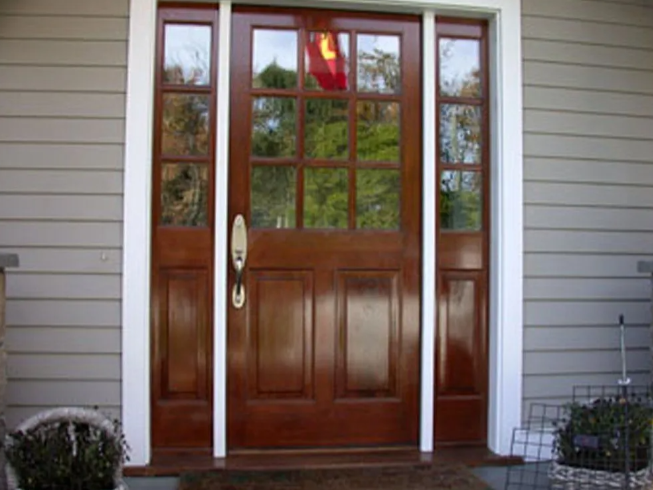 Wooden front door with glass panes and a white frame on a house porch
