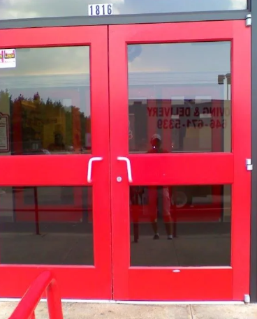 Red double glass entrance doors with silver handles and the number 1816 above them