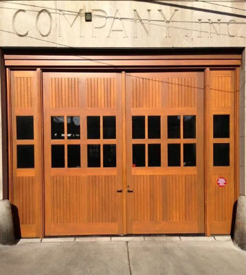 Wooden garage-style storefront doors under a “Company” sign, with small windows and side door panels
