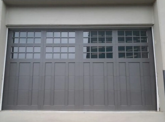 Gray garage door with small window panes across the top, set in a concrete opening