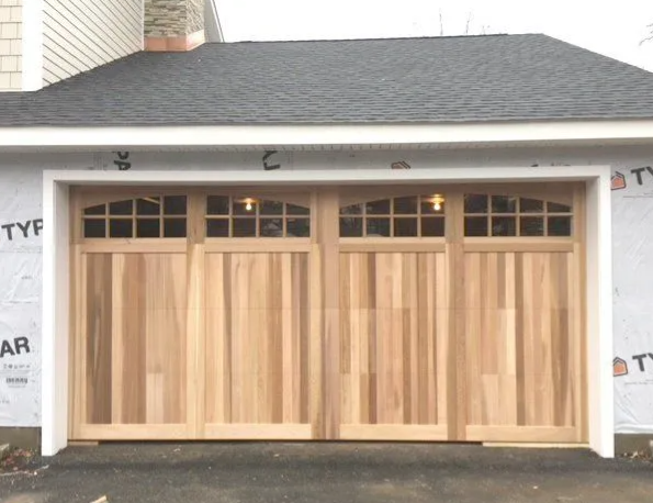 Wooden double garage door under a gray roof on a house exterior