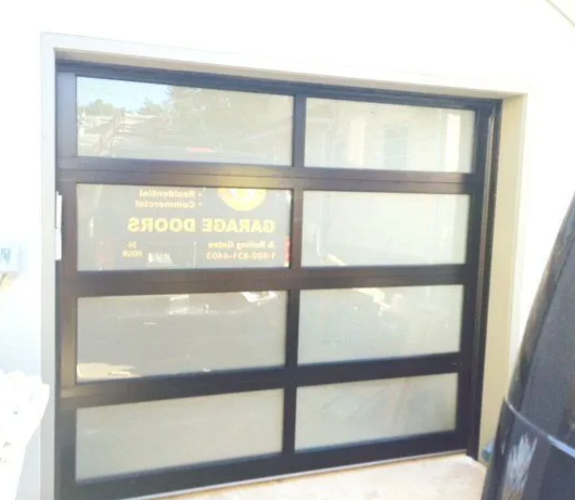 Black-framed glass office window reflecting a reversed sign and indoor light