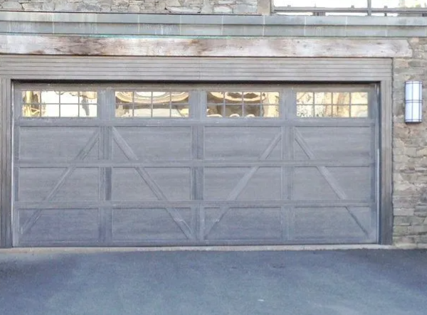Gray paneled garage door with small windows across the top