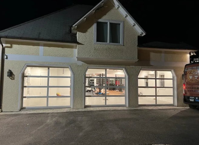 Two-car garage with lit frosted windows and beige house facade at night