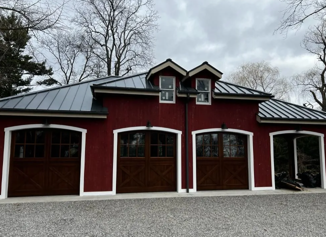 Red barn-style garage with white trim and arched doors under a cloudy sky