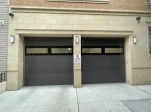 Two side-by-side gray garage doors on a beige building facade