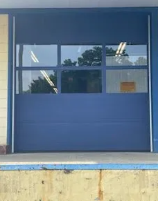 Blue storefront with large windows and a closed door, seen from outside