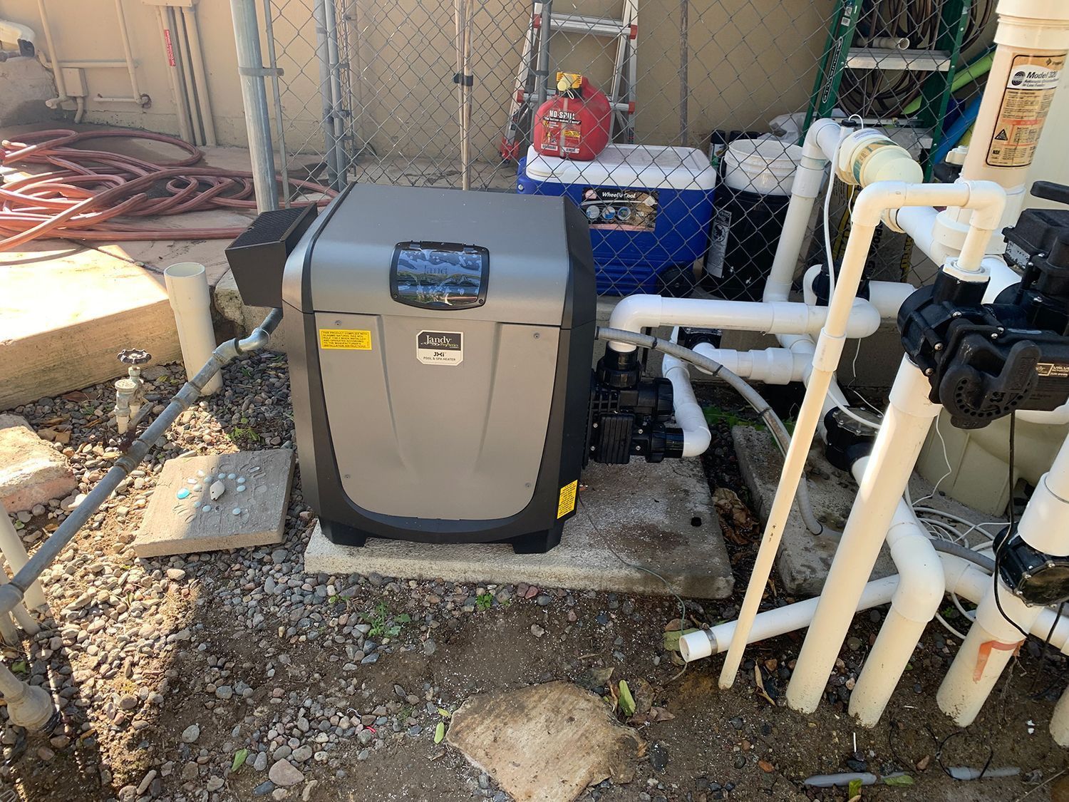 Pool heater and equipment, grey and white, outdoors.