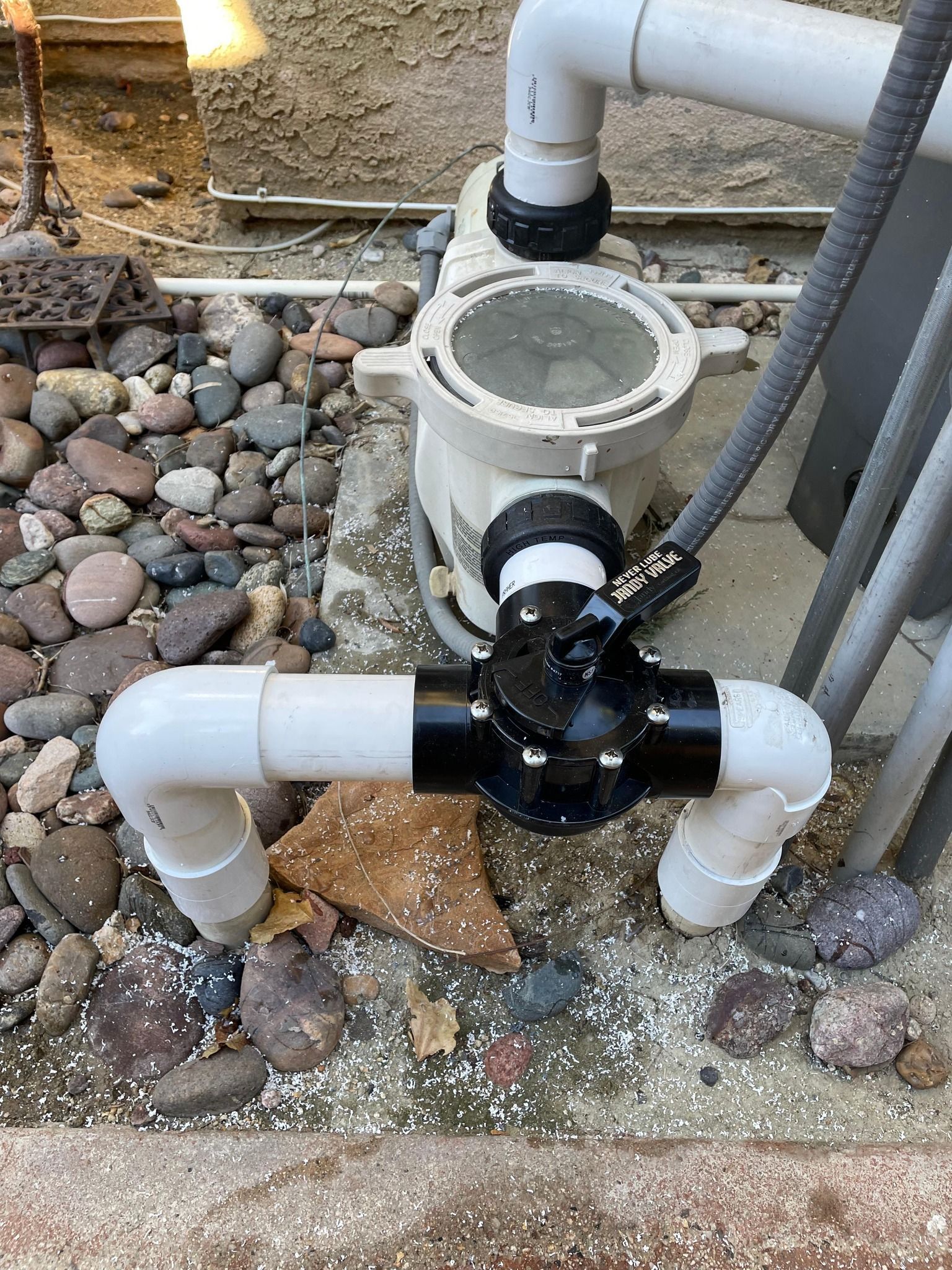 Pool pump and filter system with PVC piping and a black valve.