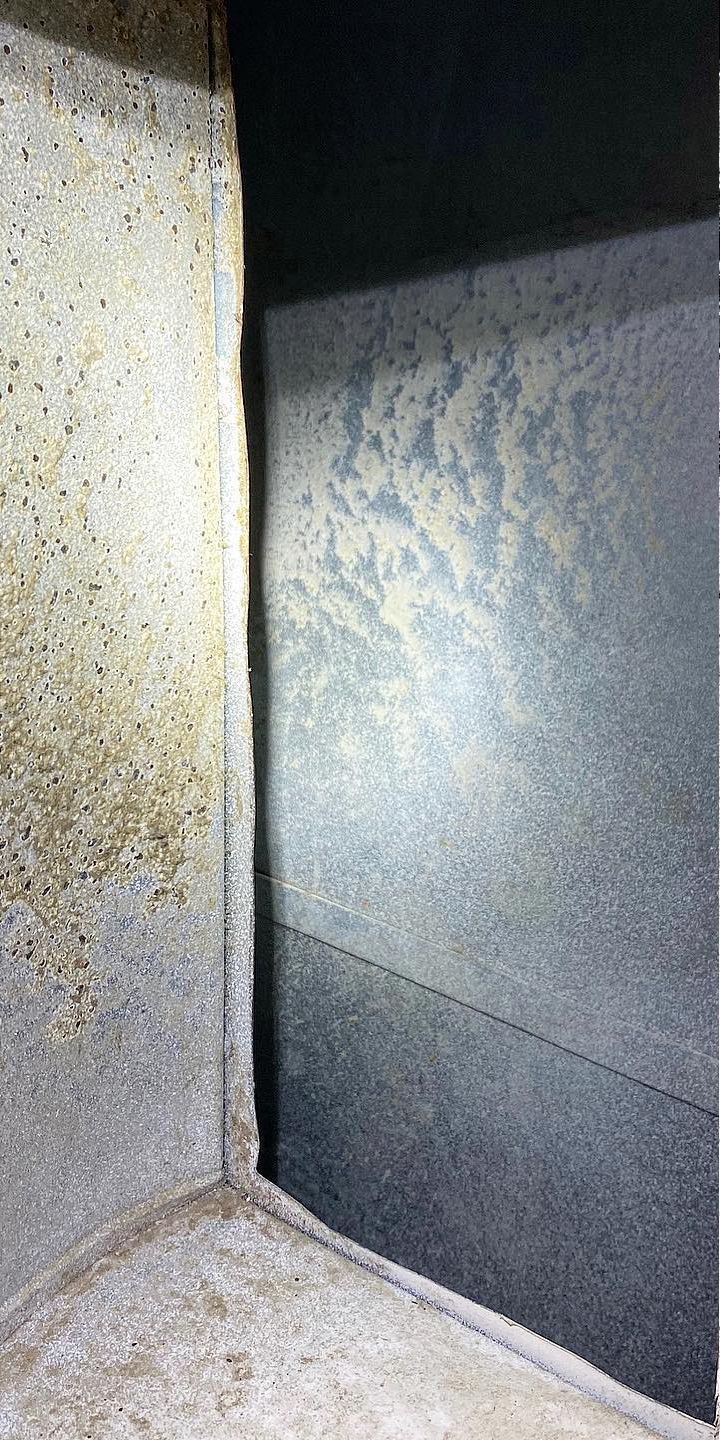 Corner of a dark interior space with mottled gray walls and a visible seam.
