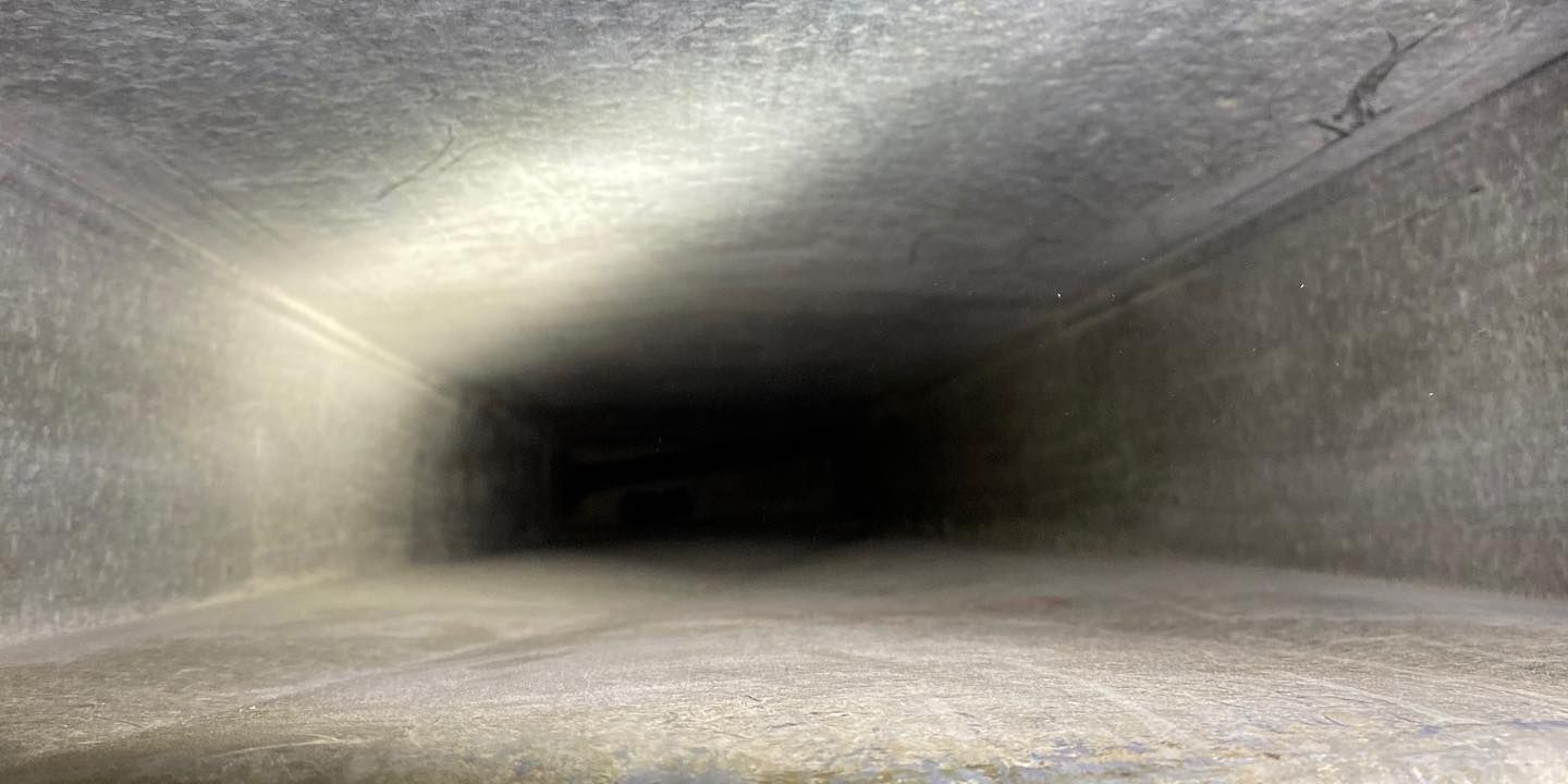 Inside of a rectangular, dusty duct, fading to dark at the end.