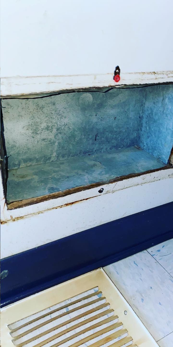 Open, rectangular built-in wall box with gray interior and white frame, a red object on top.