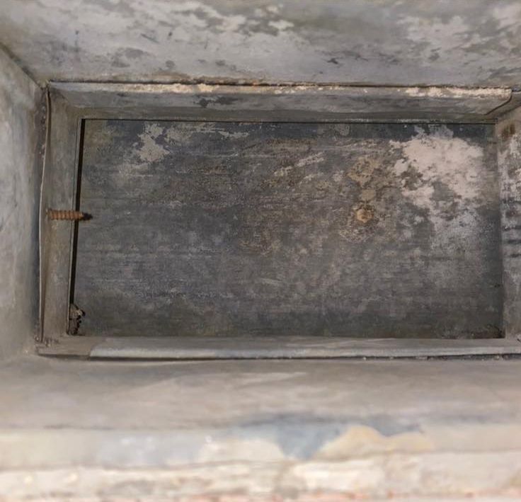 Rectangular metal duct interior; metal panel in center, attached by a screw.