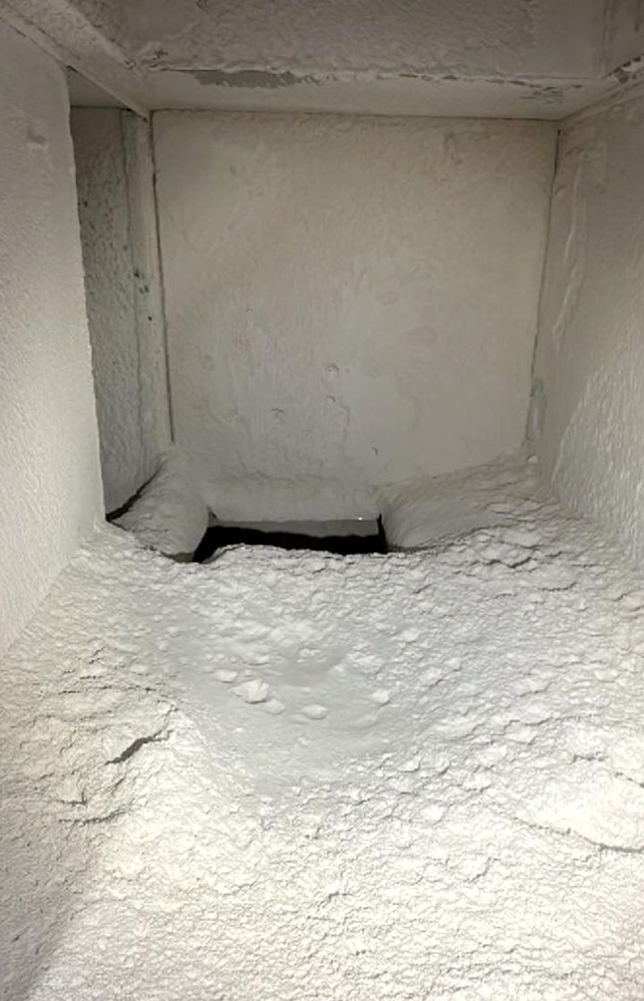 A rectangular, dusty white space, possibly a utility shaft or a chimney, with a dark opening at the base.