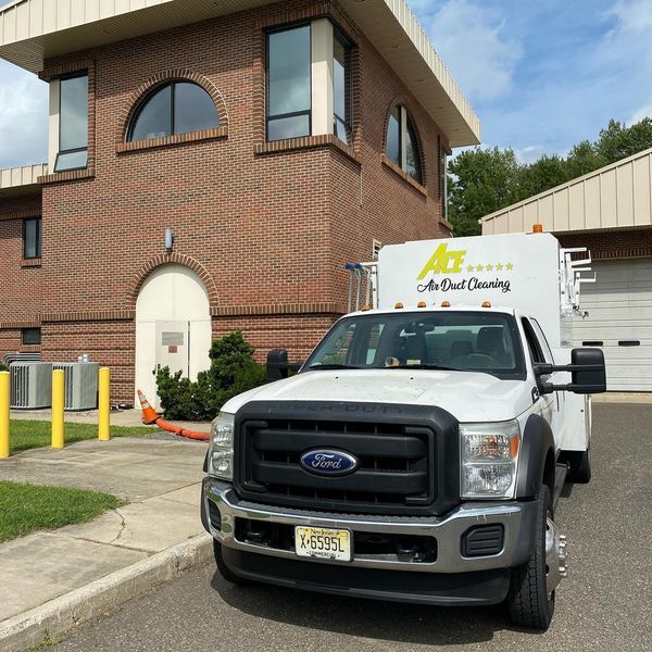 White Ford truck with “All Clean Cleaning” parked in front of a brick building.