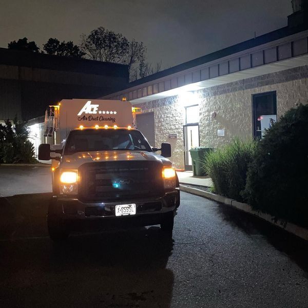 Truck with lights on, parked near a building at night.