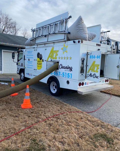 White Ace Cleaning truck parked in front of a house, hose extended, orange cones on the ground.