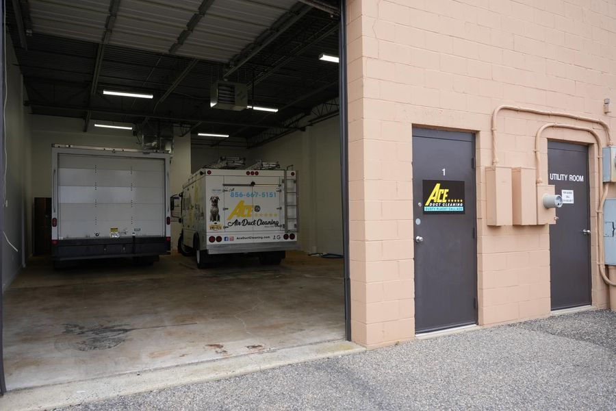 Trucks parked inside a loading dock, beside brown doors. Building exterior is beige.