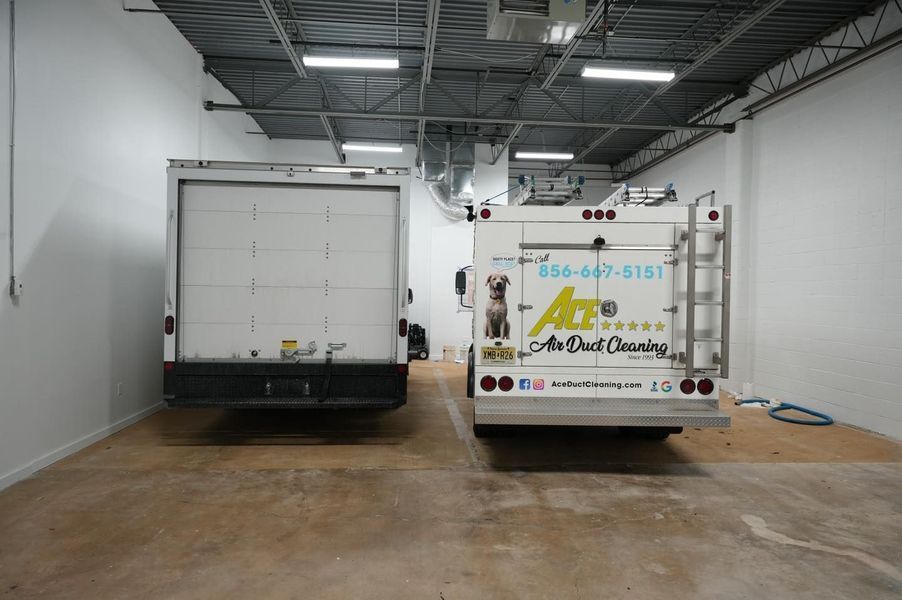 Two white trucks parked inside a building, one with a rear door, and the other with 
