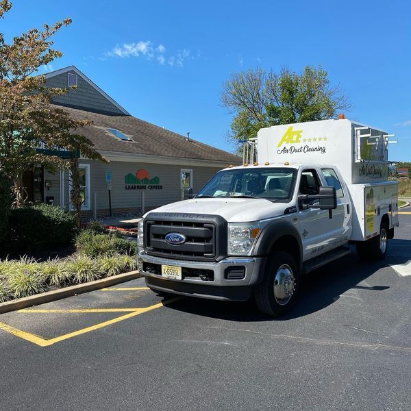 White Ace Heating and Cooling service truck parked in front of a building with a green awning.