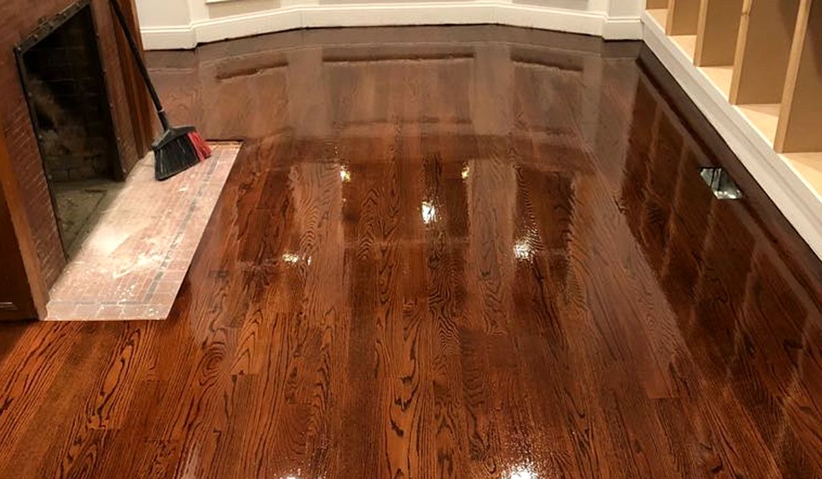 Shiny hardwood floor in an empty room with a fireplace and stairs