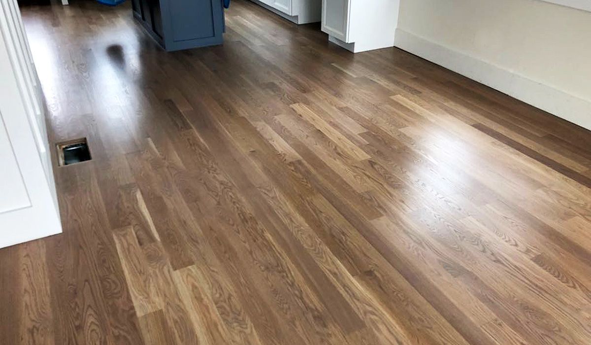 Empty room with glossy hardwood floors and sunlight reflecting across the floor.