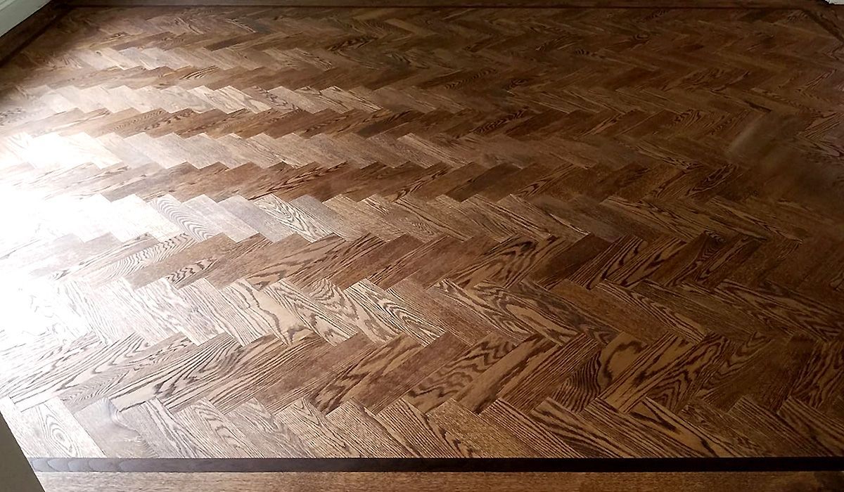 Close-up of a light brown wood floor with visible grain and reflected light.