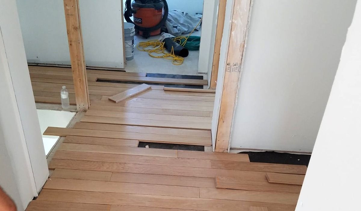 Damaged hardwood floor with missing boards in a house hallway under renovation