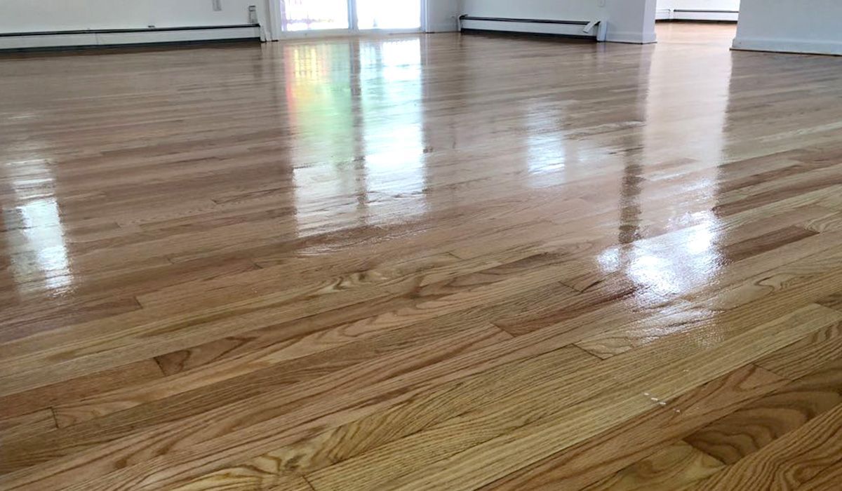 Shiny hardwood floor in an empty room with reflections from windows