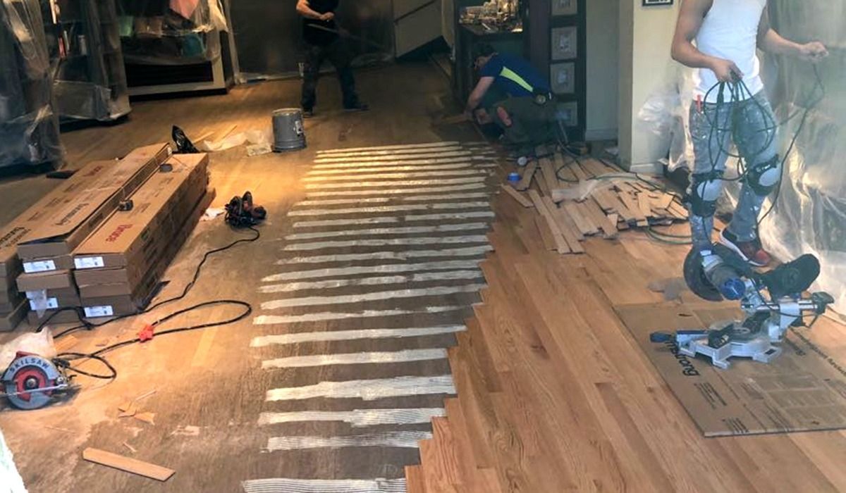 Living room with striped runner, scattered wood planks, tools, and a person working on the floor