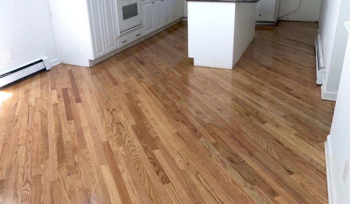 Empty kitchen with hardwood floors, white cabinets, and a small island.