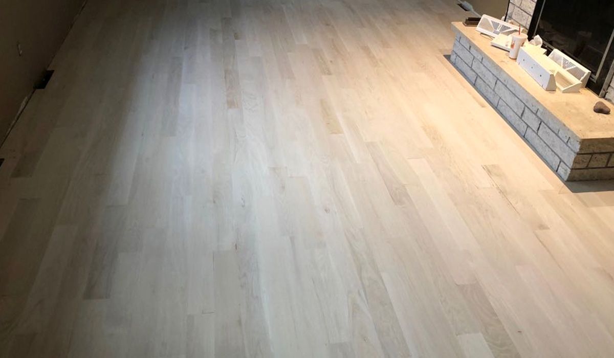 Empty light wood floor with a small brick-lined fireplace or hearth on the right side.
