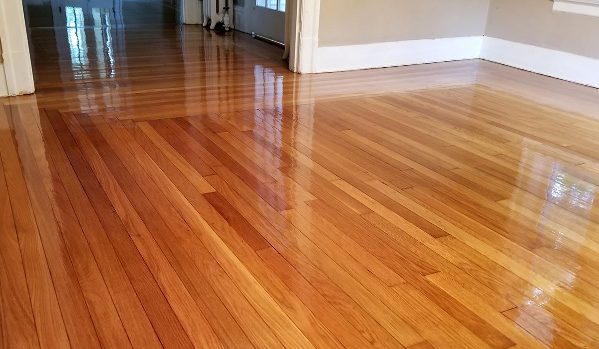 Shiny hardwood floor in a hallway and room with white walls and beige trim