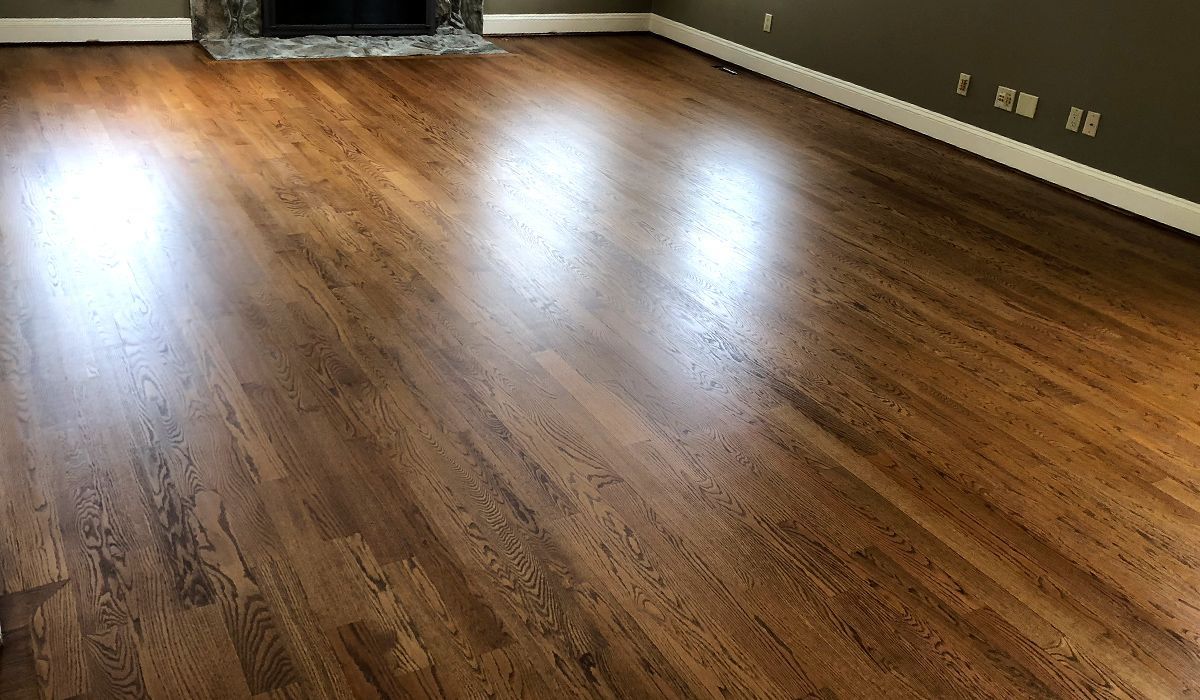 Empty room with polished hardwood floors and sunlight reflections