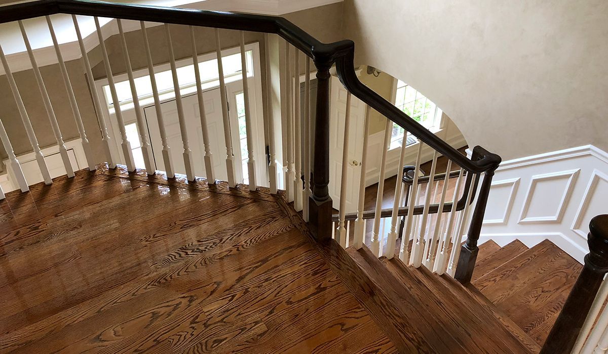 Curved wooden staircase with white balusters and a dark handrail in a house interior