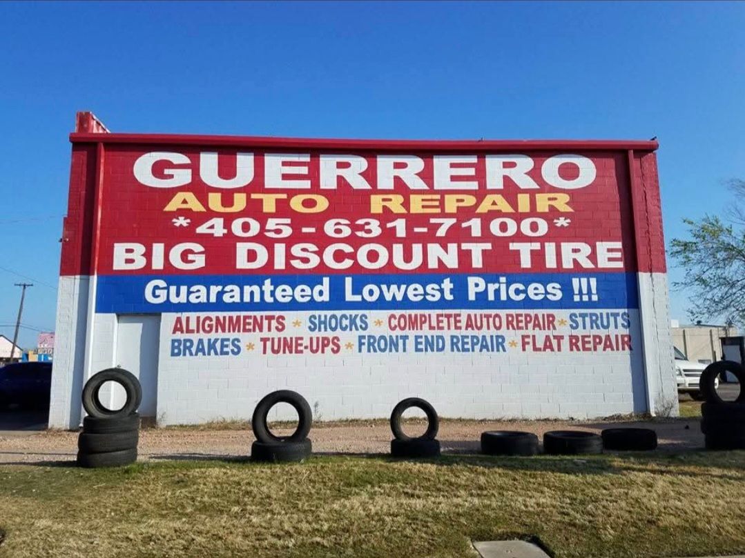 Guerrero Auto Repair roadside sign with phone number and services listed, red and white on a grassy lot.